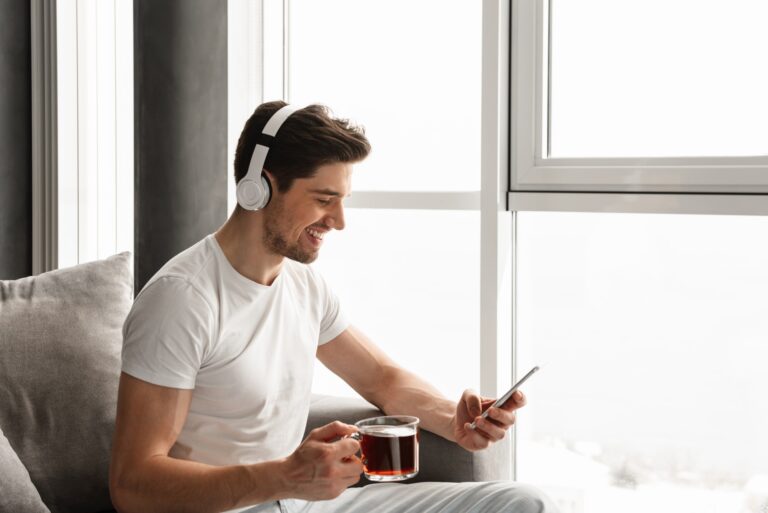 Photo in profile of smiling guy listening to music on cell phone