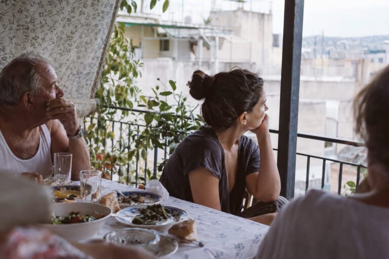 Οικογένεια κάθεται γύρω από τραπέζι και μιλά, αποτυπώνοντας προσδοκίες που διαμορφώνουν σχέσεις και πώς να αλλάξουν.