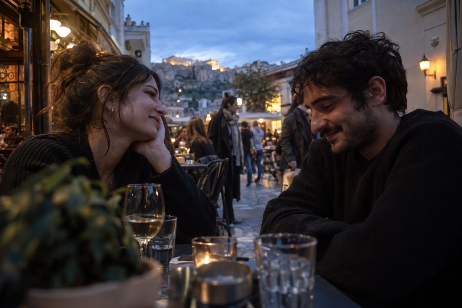 Δύο άτομα σε τραπεζάκι καφέ χαμογελούν καθώς συζητούν, προτείνοντας ερωτήσεις για το πρώτο ραντεβού.