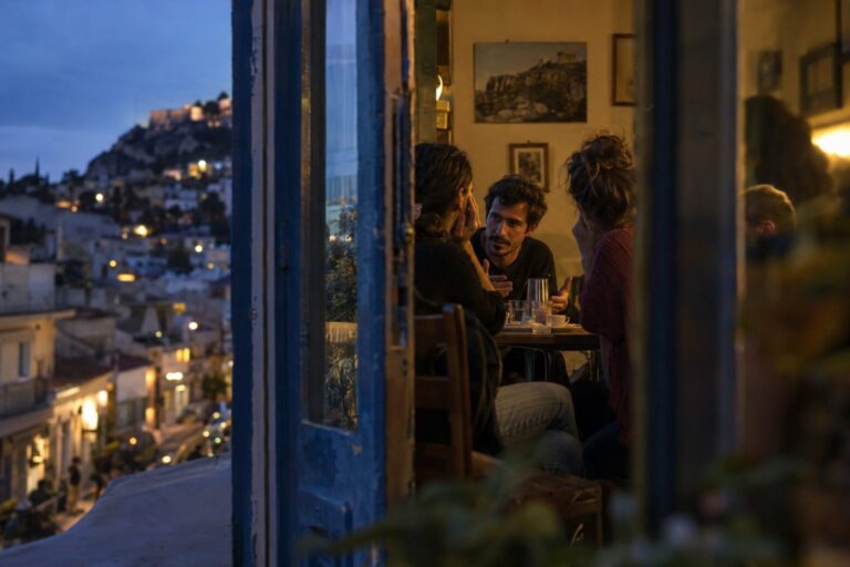 Τρία άτομα γύρω από τραπέζι συζητούν ήρεμα για να διαχειριστούν τη διαφωνία χωρίς βλάβη στη σχέση.