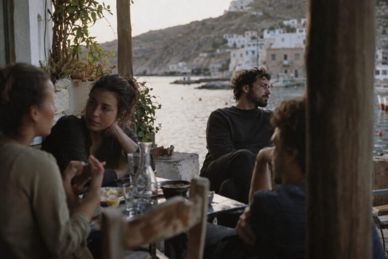 Ζευγάρι σε σαλόνι, ο σύντροφος φαίνεται δυσαρεστημένος ανάμεσα σε φίλους· πρακτικός οδηγός σχέσεων.