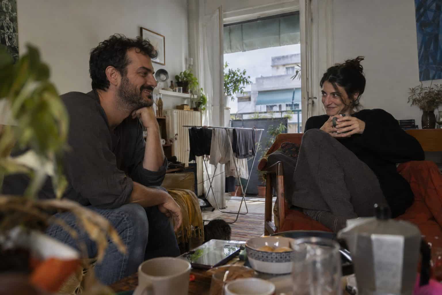 Δύο άτομα σε καφέ χαμογελούν και ανταλλάσσουν μήνυμα, προετοιμάζοντας φλερτ μετά μακροχρόνια σχέση.