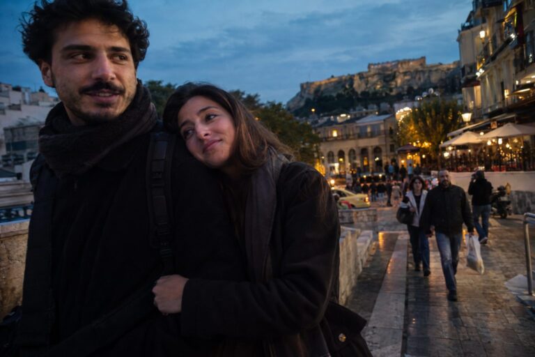 Ζευγάρι με μπουφάν σε κεντρικό ελληνικό δρόμο, χειμωνιάτικη ατμόσφαιρα συνδέεται με cuffing season.