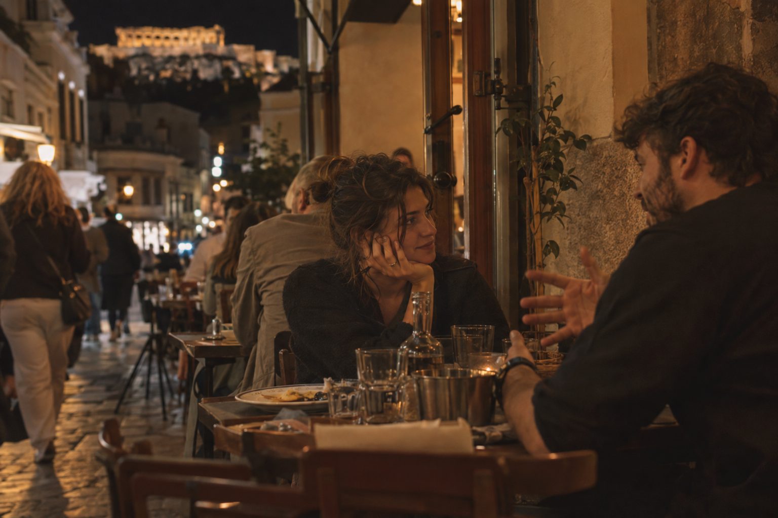 Ζευγάρι κάθεται σε τραπέζι με λογαριασμούς και νομίσματα, μιλώντας ήρεμα για χρήματα.