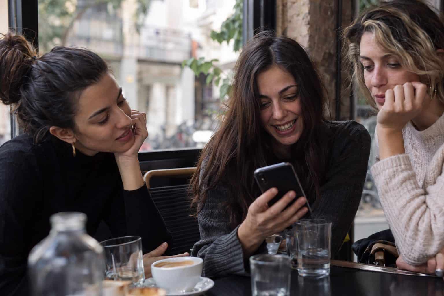 Κοντινό πλάνο smartphone με ανοιχτή ομαδική συνομιλία, εικονίδια προσώπων και συζητήσεις για δεύτερο ραντεβού.