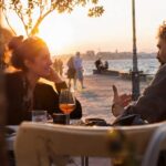 Δύο άτομα σε πρώτο ραντεβού καθισμένα σε τραπέζι καφέ, κοιτάζονται, χαμογελούν και συζητούν αξίες όπως ειλικρίνεια.