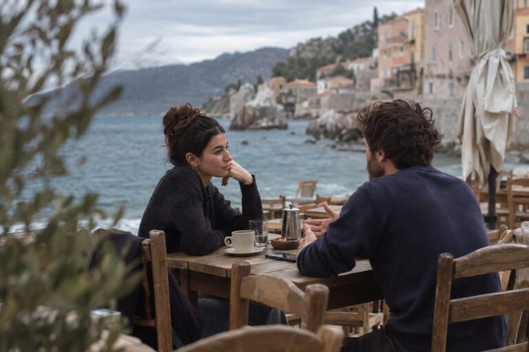 Ζευγάρι κάθεται ήρεμα στο σαλόνι, κοιτάζει λογαριασμούς και νομίσματα, και συζητά για τα χρήματα χωρίς καβγά.