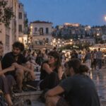 Άτομα σε ανοιχτό χώρο συζητούν γύρω από τραπέζι, συνδέοντας τη σχεσιακή αναρχία με την Ελλάδα 2026.