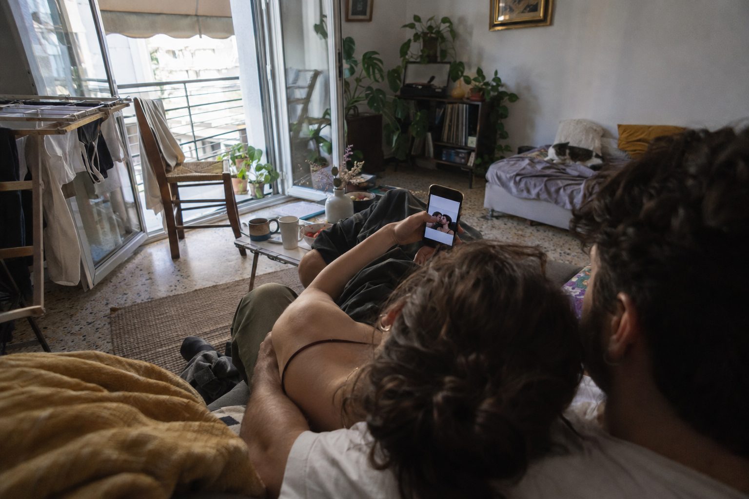 Ζευγάρι χαμογελά μπροστά σε κινητό, συνδέοντας τη σκηνή με soft ή hard launch ανακοίνωσης σχέσης στα social.