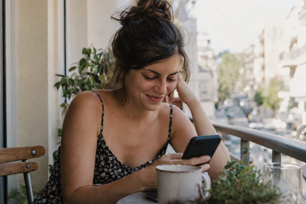 Ζευγάρι κάθεται σε παγκάκι, ανταλλάσσει μηνύματα στο κινητό μετά το πρώτο ραντεβού, απεικονίζοντας το θέμα.