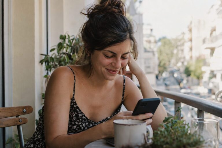 Ζευγάρι κάθεται σε παγκάκι, ανταλλάσσει μηνύματα στο κινητό μετά το πρώτο ραντεβού, απεικονίζοντας το θέμα.